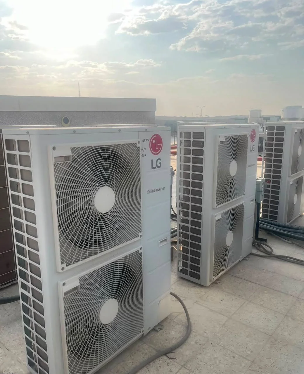 شركة الريان شراء اجهزة كهربائية مستعملة بالرياض صورة حقيقية لثلاث وحدات تكييف خارجية كبيرة من إل جي بمروحتين، مركّبة على سطح مبنى